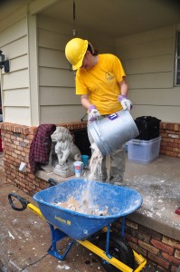 A Baptist mud-out volunteer pours a bucketful of debris into a wheel barrel to be hauled off. (Photo: David Crowell)