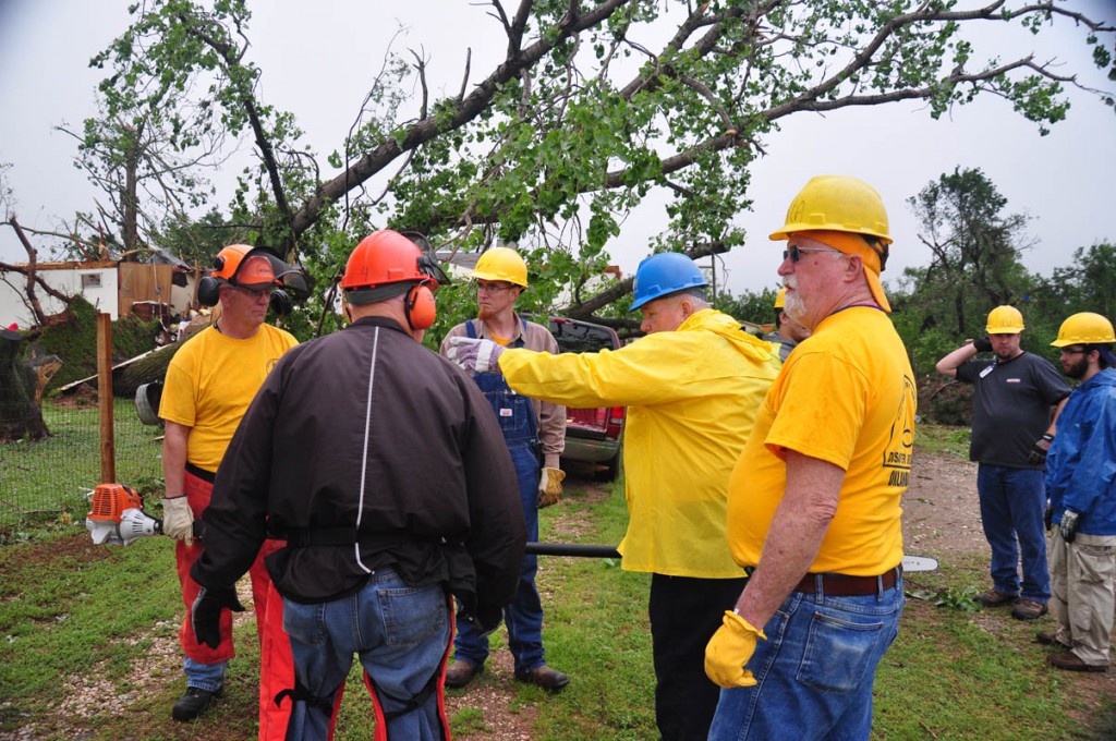 Debris removal team leader Deyrl Kastner (In blue hard hat) outlines plans for removing debris from a property in the Bridge Creek area. (Photo: David Crowell)