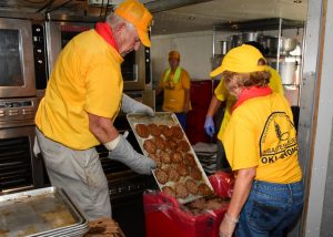 Oklahoma Disaster Relief volunteers Bob Goekler and Kendal Miller fill a container with hamburger patties to be delivered to flood victims. (Photo: David Crowell)